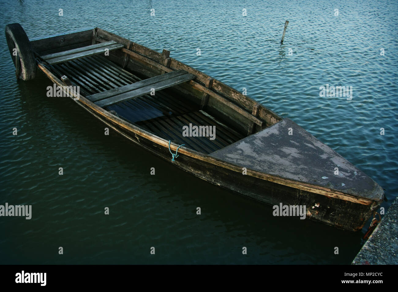 A close look of a very old wood fishing boat floating on the water in a ...