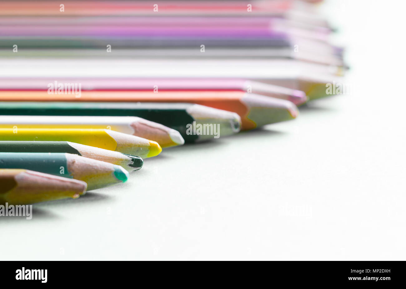 Very used pencils of different colors isolated on a green background. Concept of spare to buy new ones Stock Photo