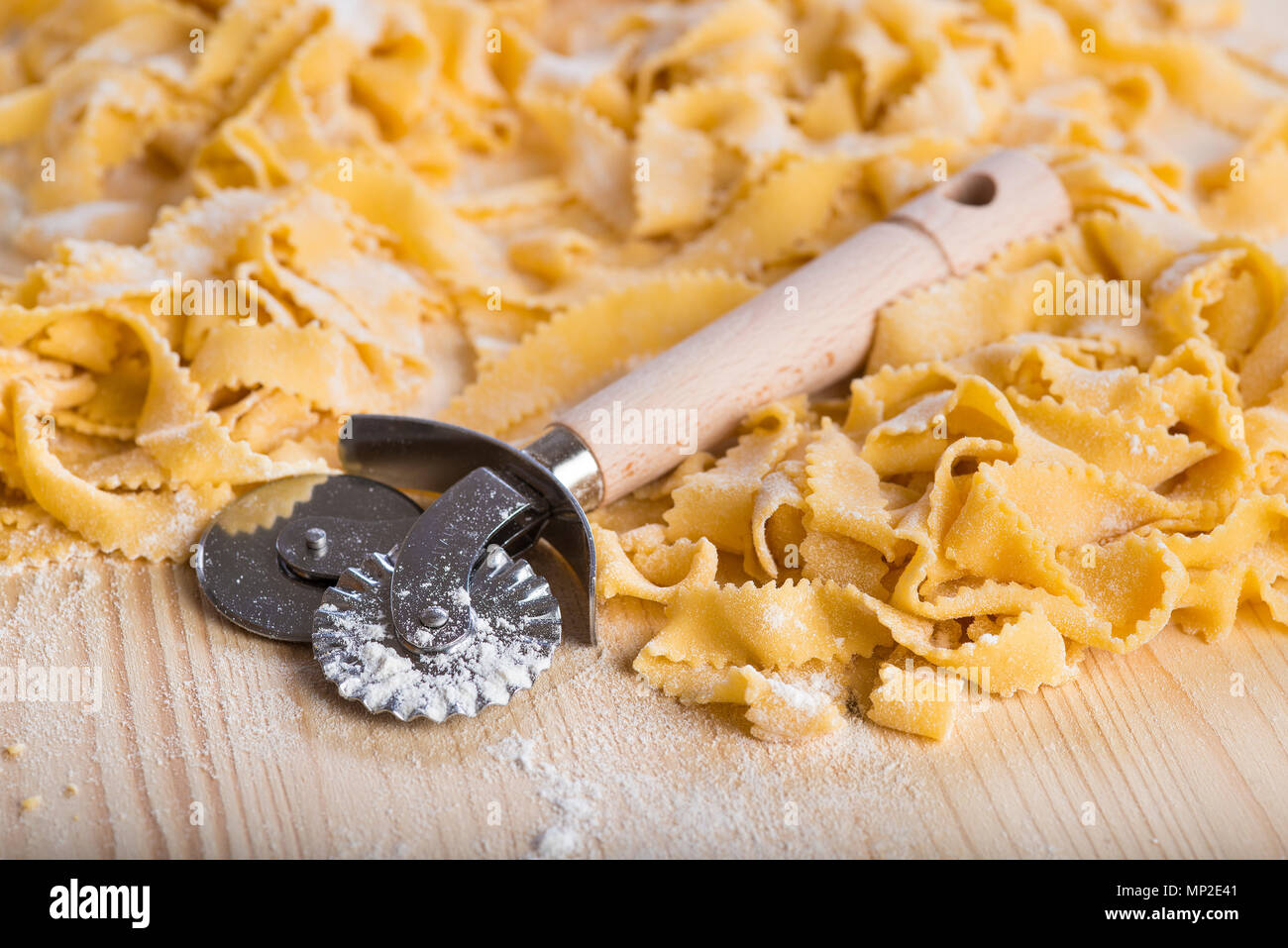 Fresh egg pasta and a dough cutter wheel to prepare it Stock Photo Alamy