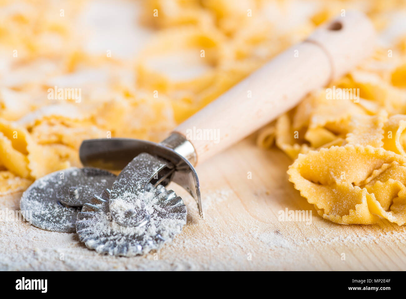 Fresh egg pasta and a dough cutter wheel to prepare it Stock Photo Alamy
