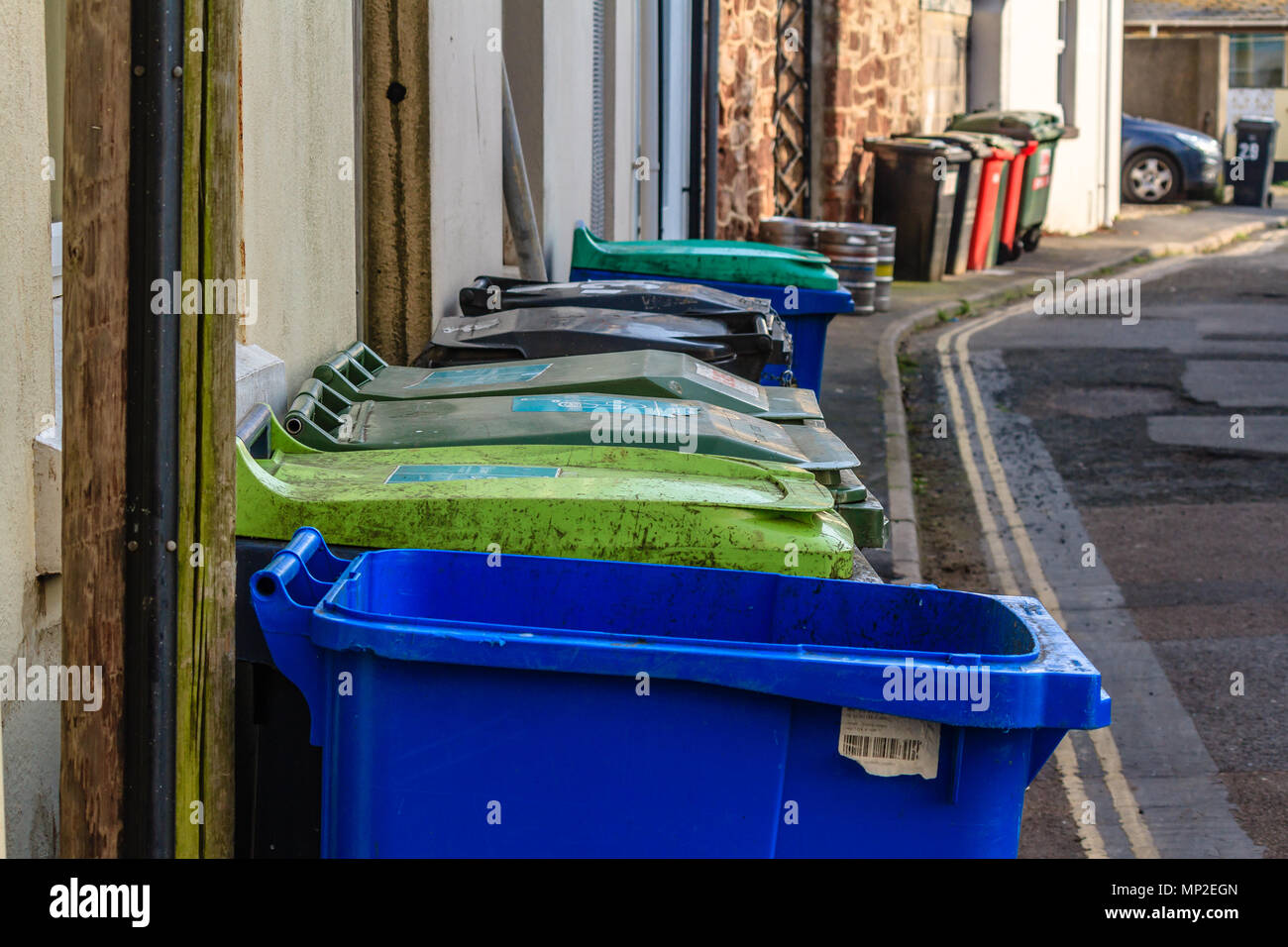 Row of large colourful domestic dustbins in a back street behind houses.  Teignmouth, Devon. Feb 2018 Stock Photo - Alamy