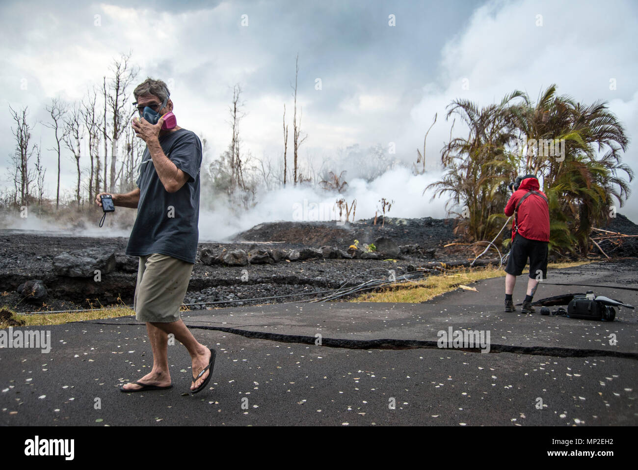 A resident wears a gas mask to protect from the harmful sulfur dioxide gases spewing from the Kilauea volcanic eruption May 18, 2018 in Pahoa, Hawaii. The recent eruption continues destroying homes, forcing evacuations and spewing lava and poison gas on the Big Island of Hawaii. Stock Photo