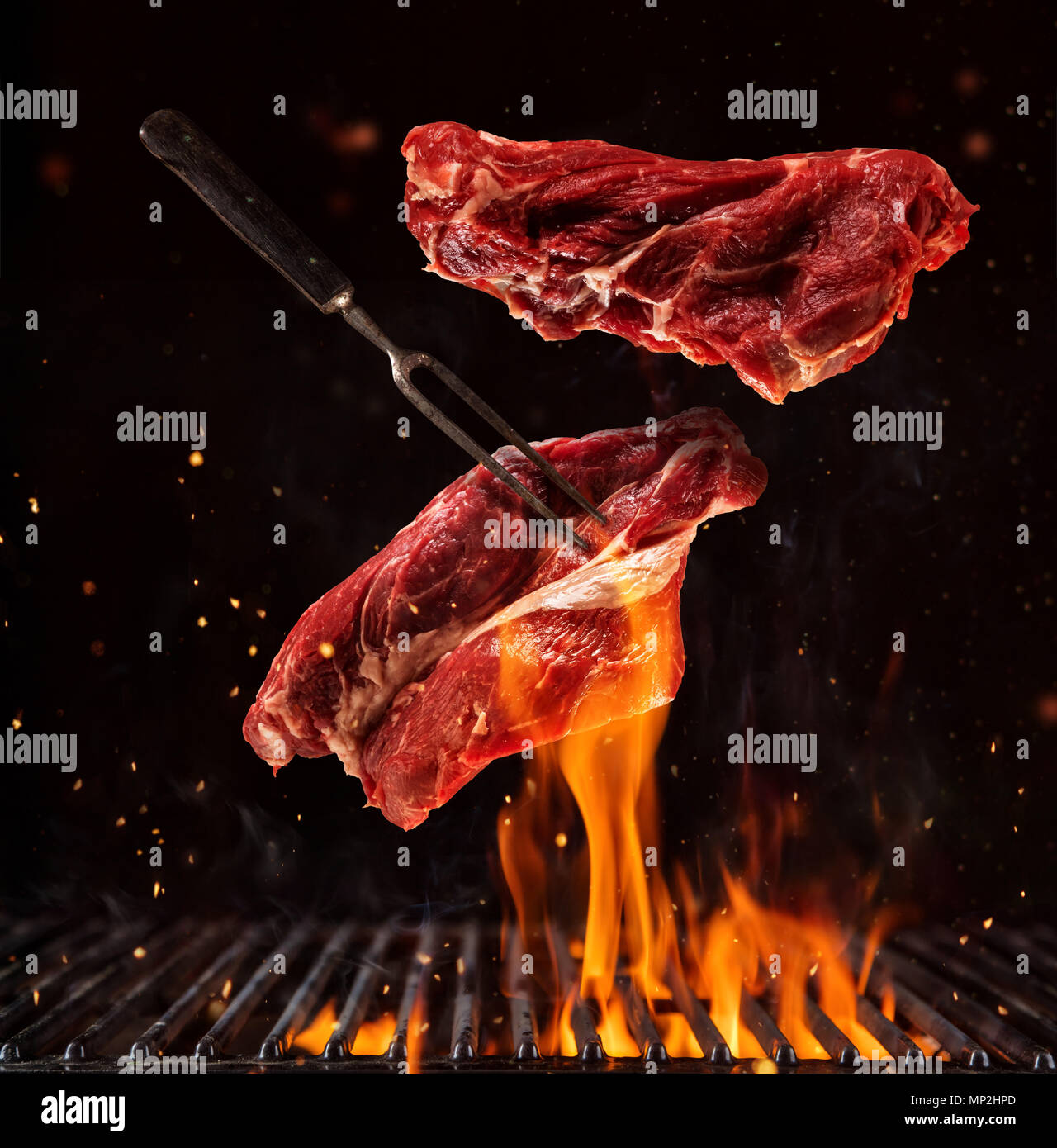 Flying pieces of beef steaks above grill grid, isolated on black ...