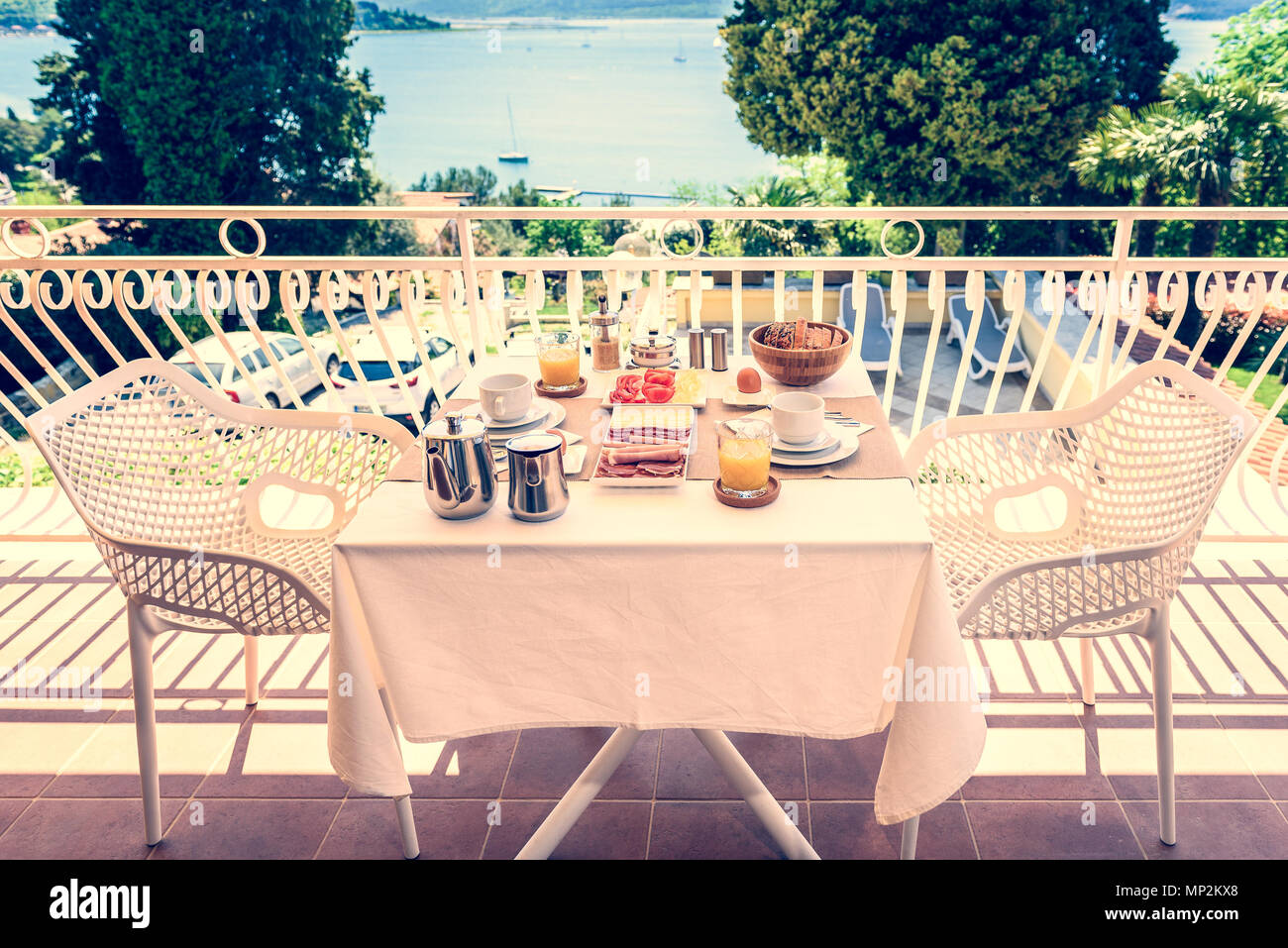 Continental morning breakfast table setting with sea view is served. Hotel restaurant buffet breakfast is served on a balcony near the ocean. Vacation Stock Photo