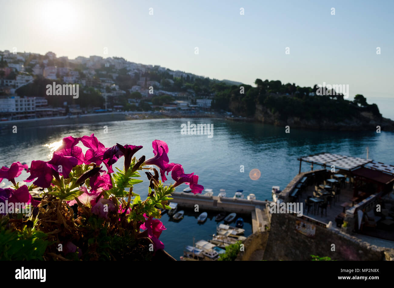 Small fishing boats marina with round pier. Wide angle shot with a city and central beach Mala Plaza on background. Ulcinj, Montenegro. Stock Photo