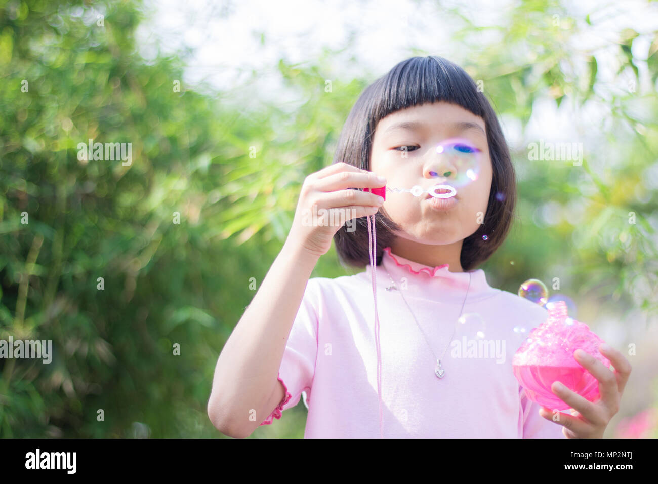 funny young girl blow bubbles in green garden Stock Photo