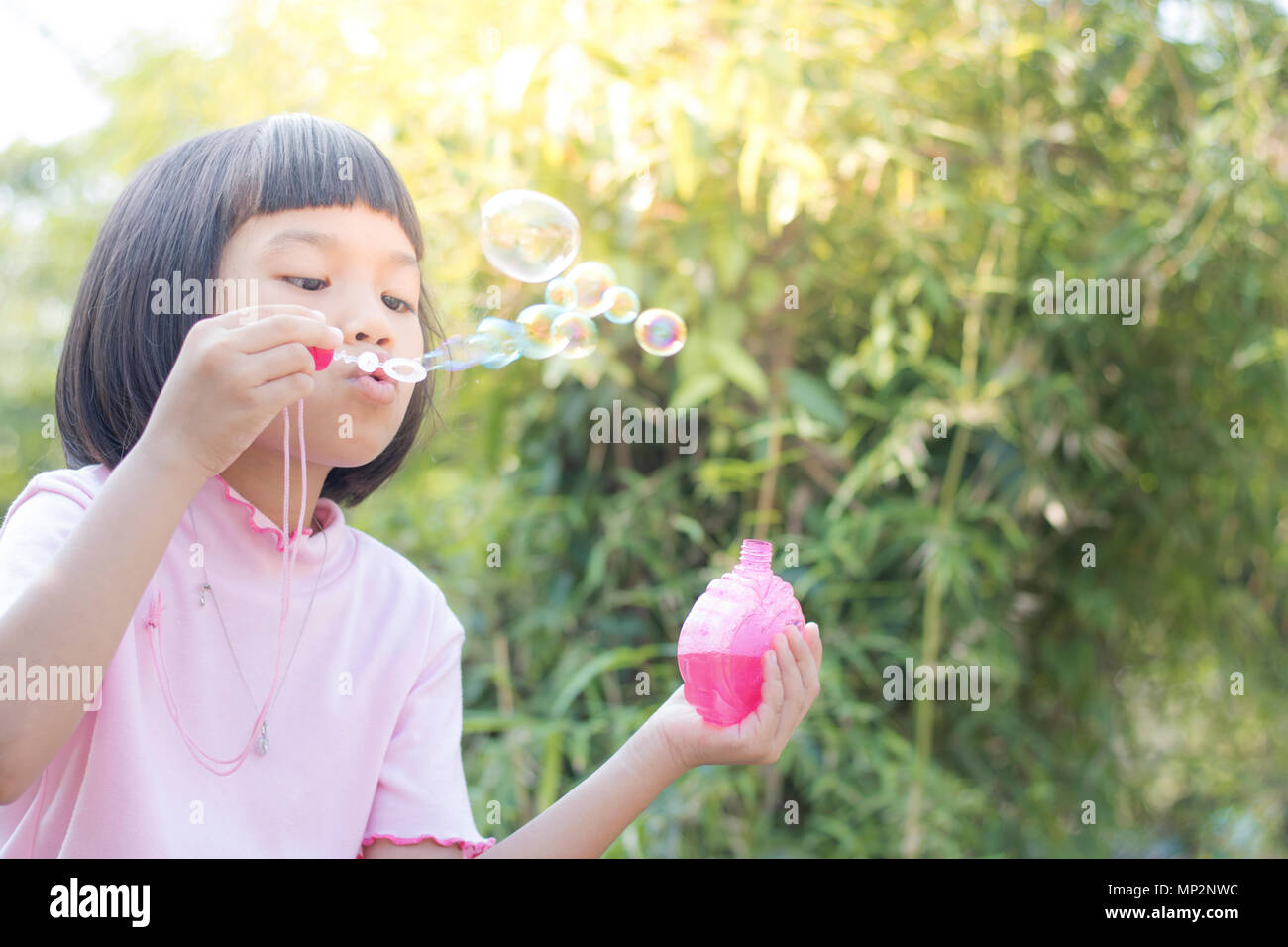 funny young girl blow bubbles in green garden Stock Photo