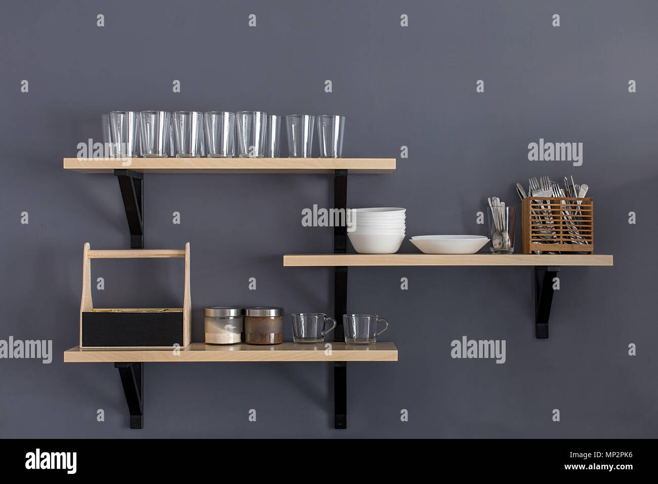 Stylish shelf with various dishware hanging on gray wall Stock Photo