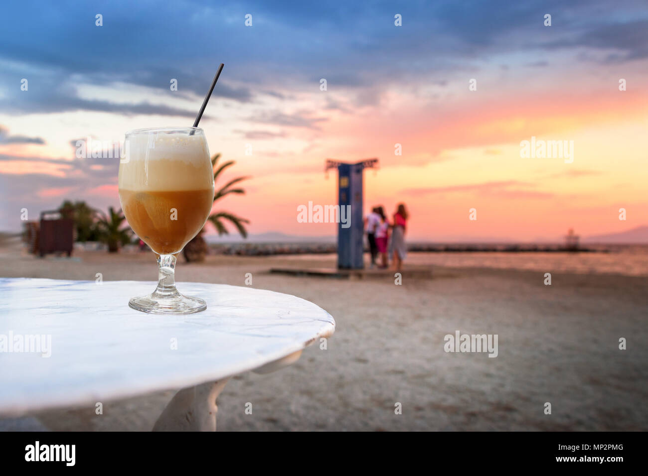 https://c8.alamy.com/comp/MP2PMG/a-glass-of-freddo-cappuccino-cold-coffee-over-a-beach-at-sunset-background-in-volos-greece-MP2PMG.jpg