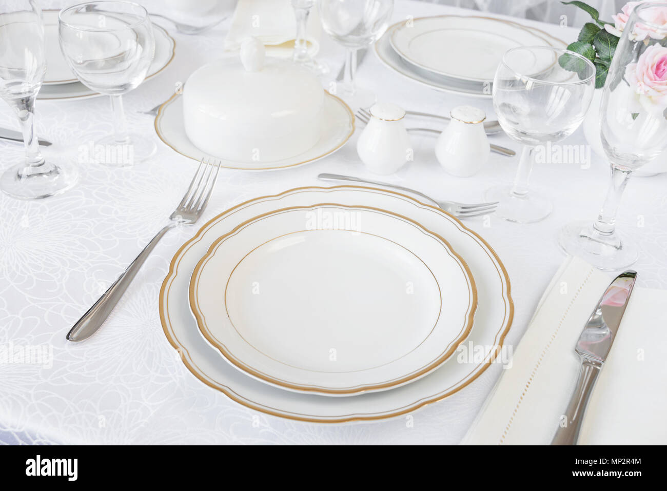 Beautifully decorated table with empty white plates, glasses, cutlery and flowers on luxurious tablecloths Stock Photo