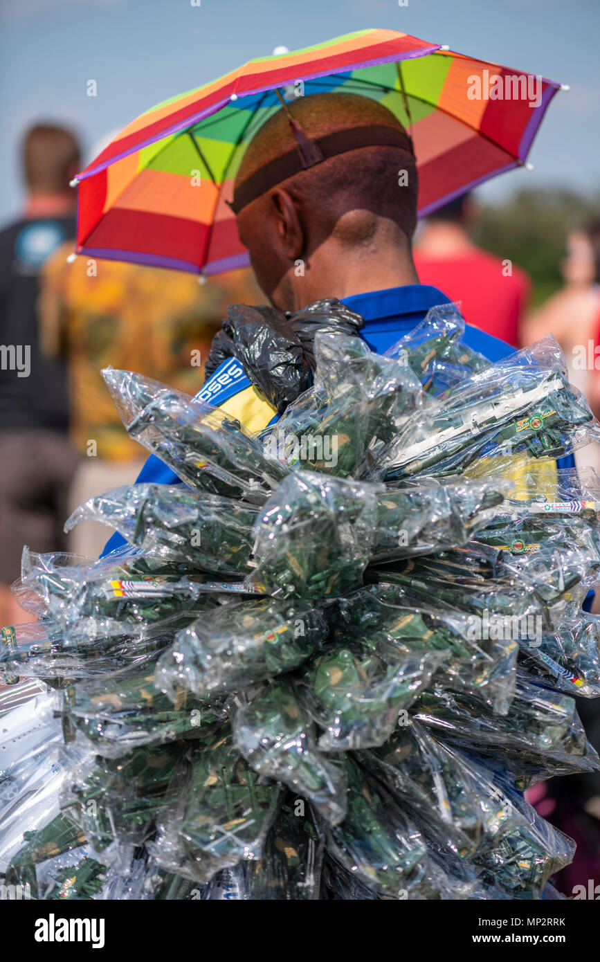 A man wearing a colorful umbrella hat and selling plastic toys at the Lowveld Airshow Stock Photo