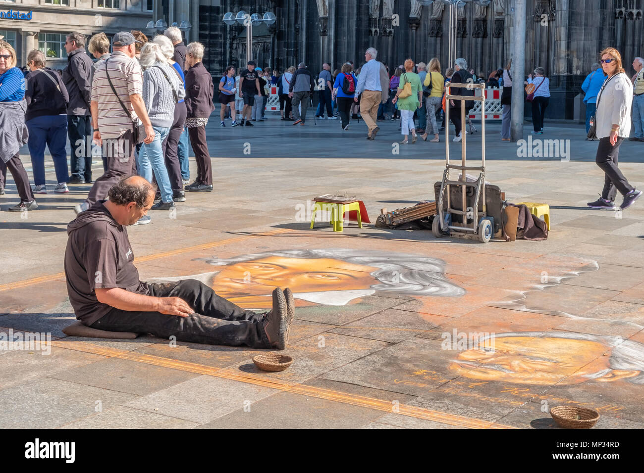 A chalk artist draws on the square near the cathedral in Cologne Germany. Stock Photo