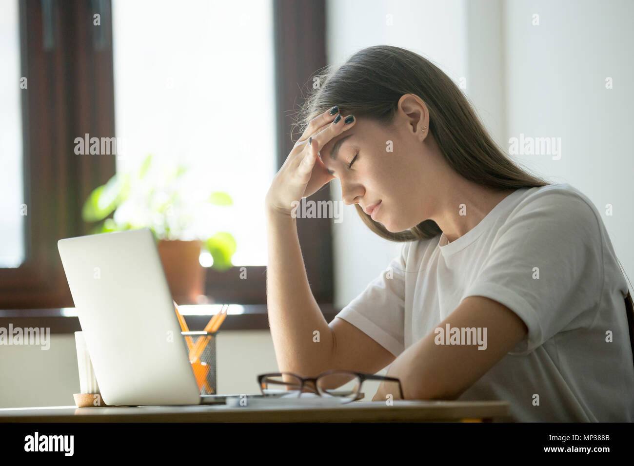 Tired female lying on table suffering from headache Stock Photo