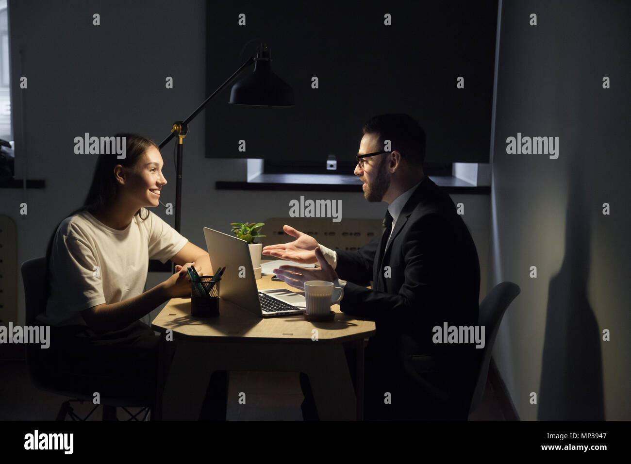 Colleagues working late hours in office discussing business plan Stock Photo