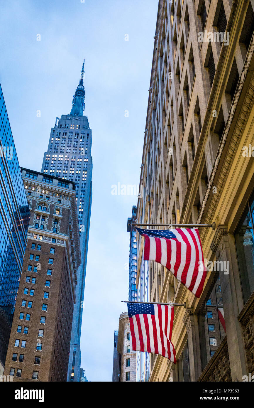 United States flags fly with the Empire State building in the background in New York City, USA. Stock Photo
