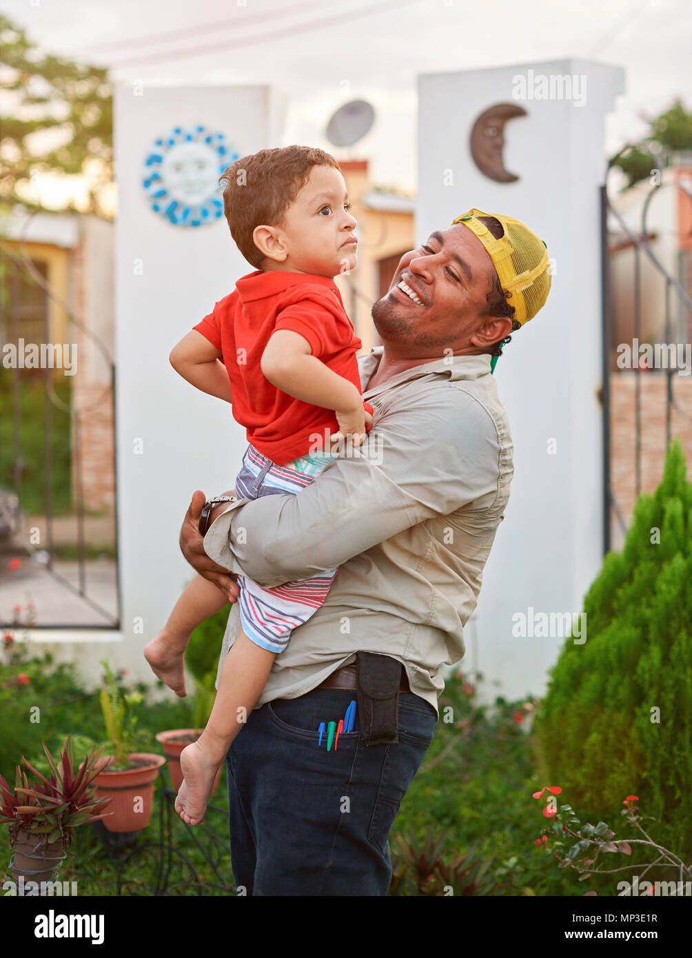 Father holding his son  in house garden after coming from work Stock Photo