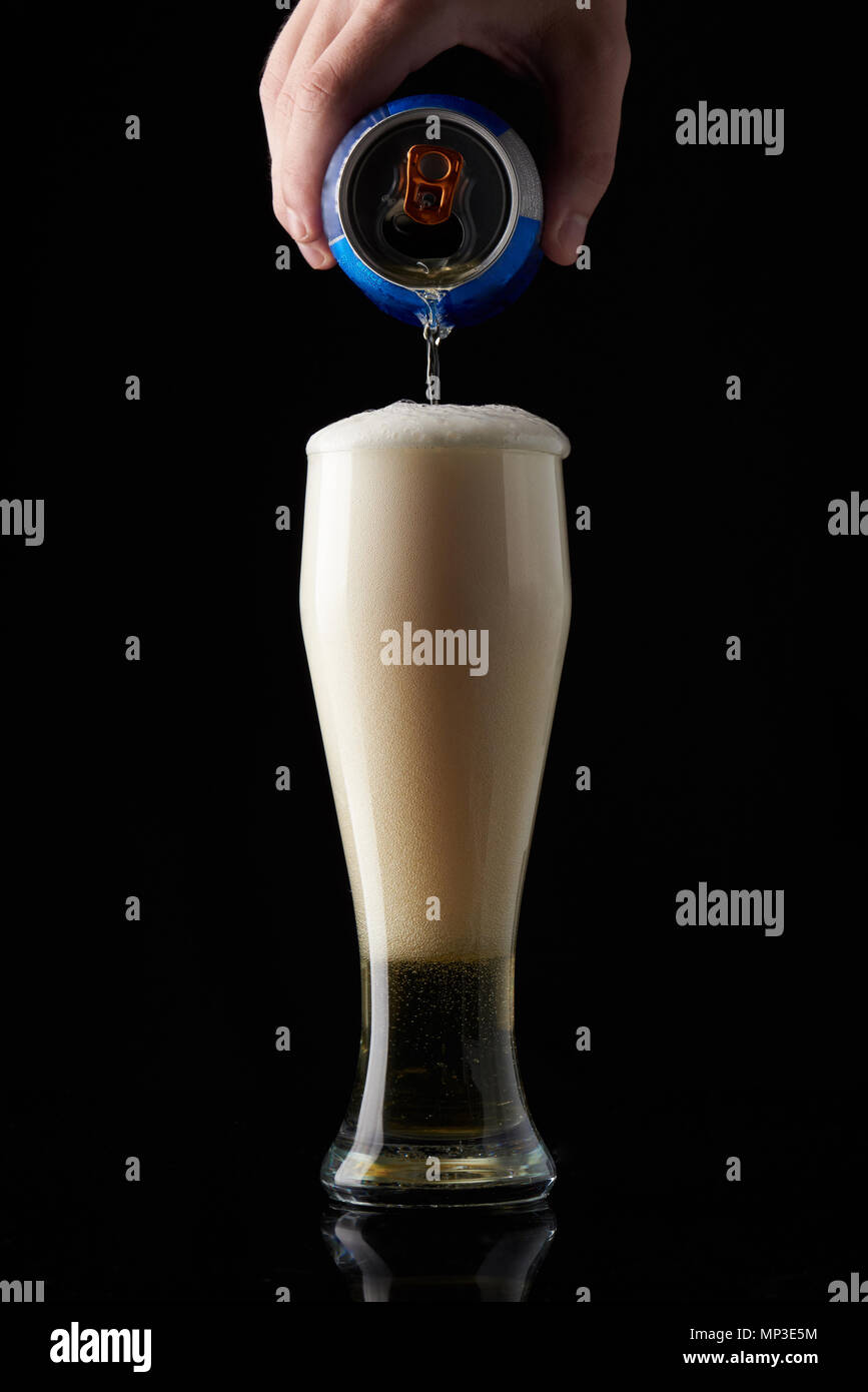Pour beer in glass from can. Big beer foam in glass Stock Photo