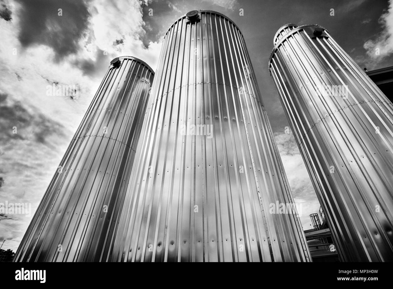 Three malt silos tower against a dramatic sky at the New Belgium Brewing Company in Asheville, NC, USA Stock Photo