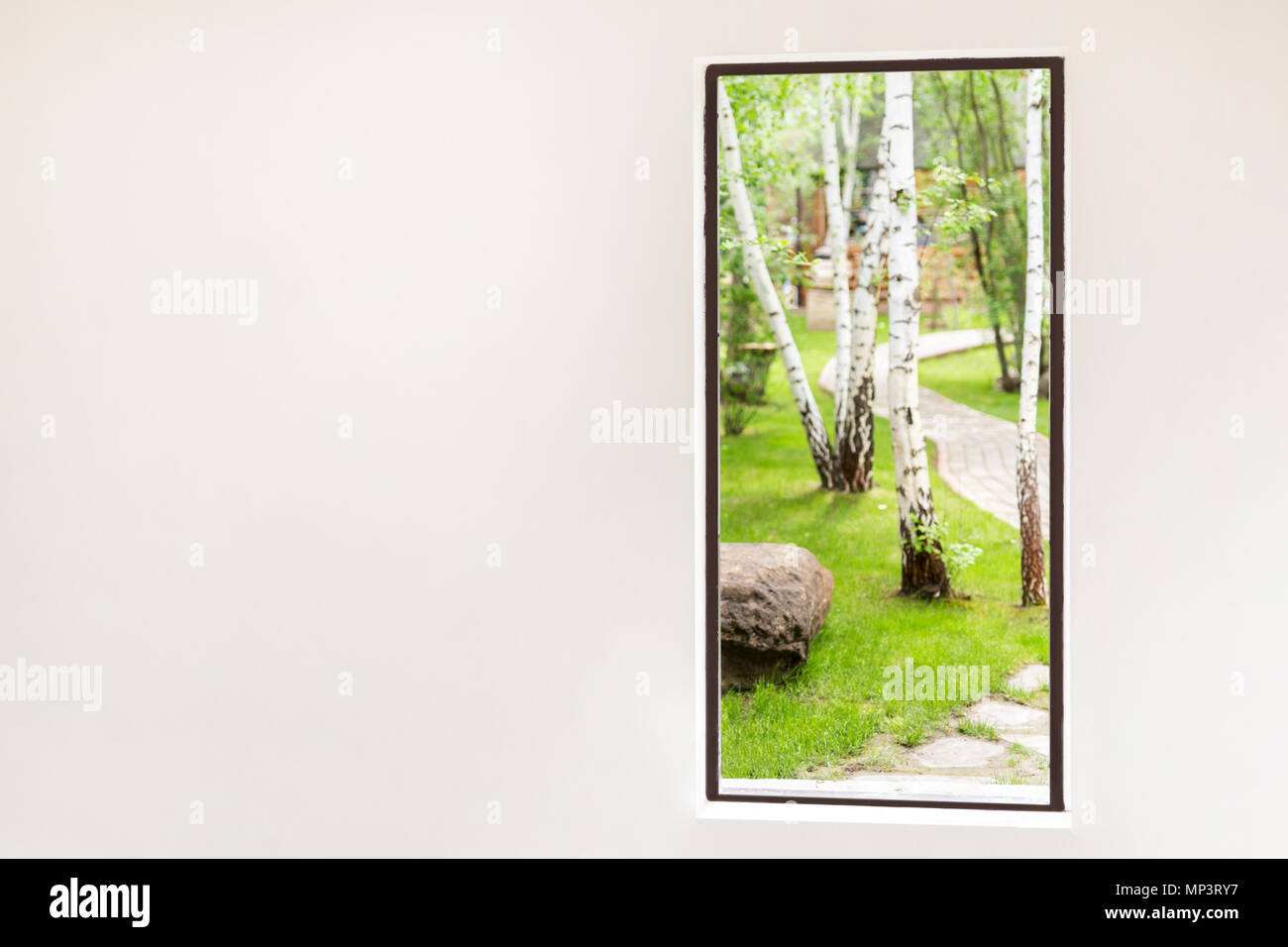 White wall with open door pass to beautiful green forest or park. Entrance to nature concept Stock Photo
