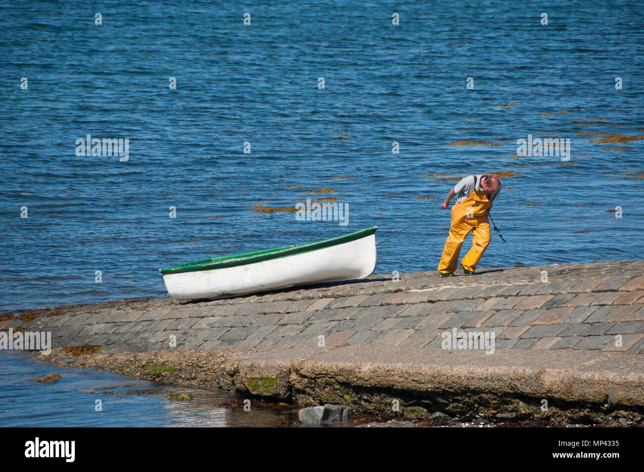 A man pulling a small boat ashore Stock Photo Alamy