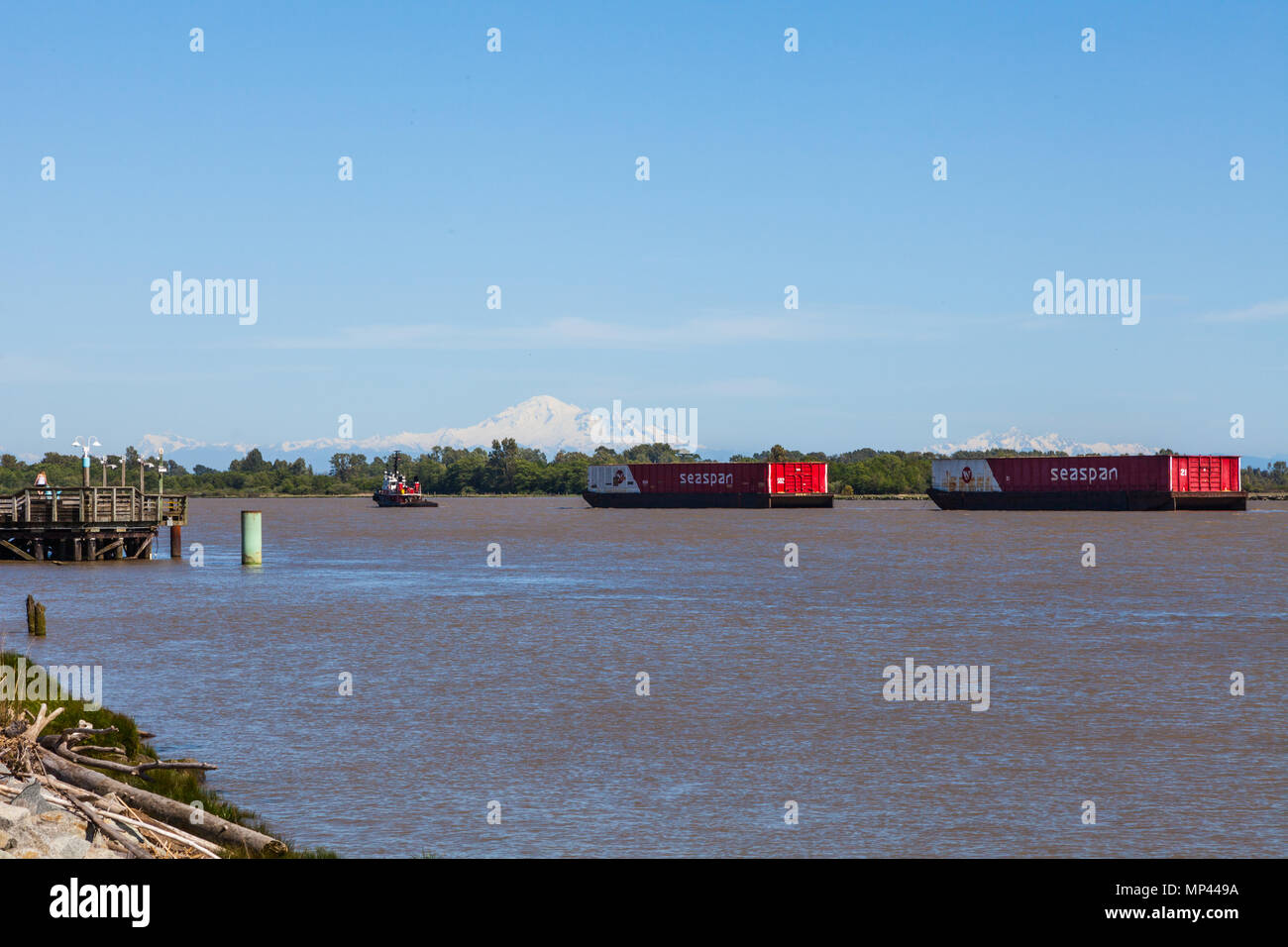 Tugboat towing two large barges up the Fraser River with Mount Baker in the background Stock Photo