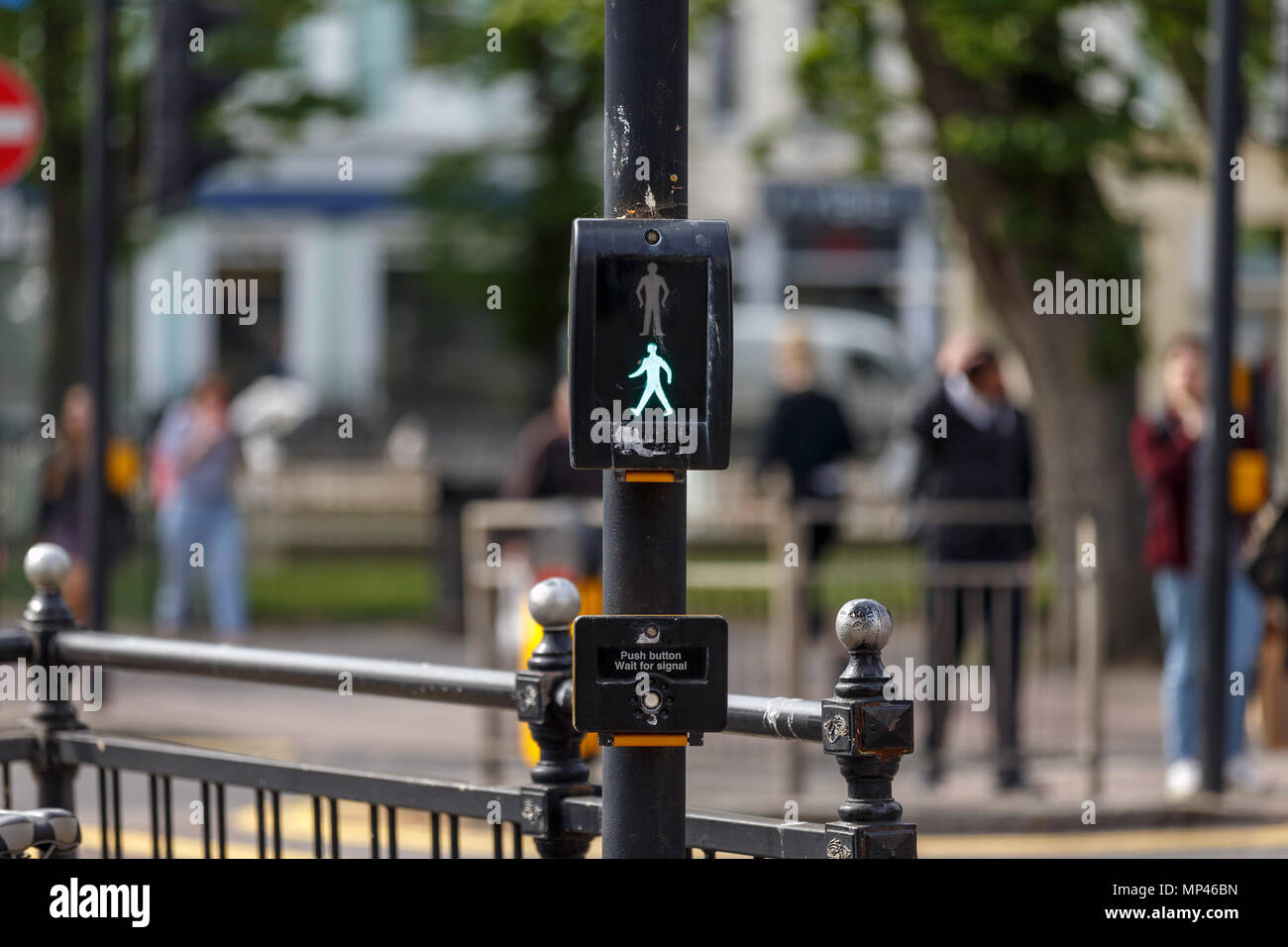 A traffic crossing in the United Kingdom with the green man illuminated, signaling that pedestrians may cross safely. Stock Photo