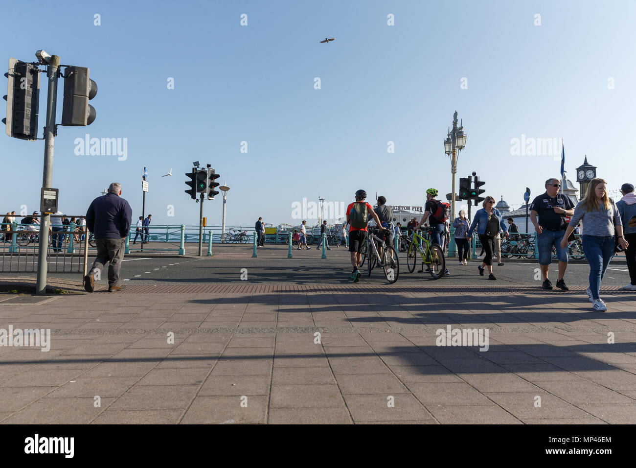 Pedestrians and cyclists crossing the road next to Brighton Palace Pier on a sunny day. Brighton, East Sussex, UK. Stock Photo
