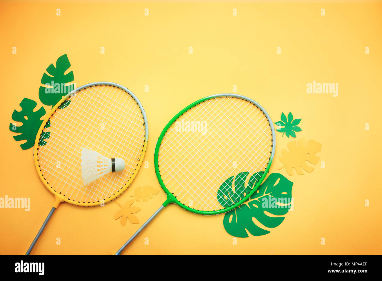 Badminton beach set. Summer activities flat lay with tropical leaves on a bright yellow background with copy space. Stock Photo