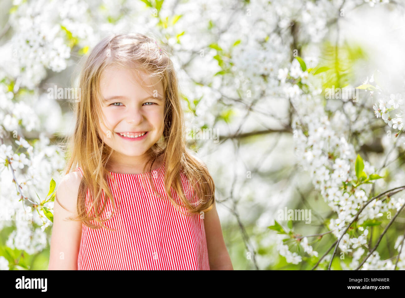 Happy little girl in cherry blossom garden Stock Photo - Alamy