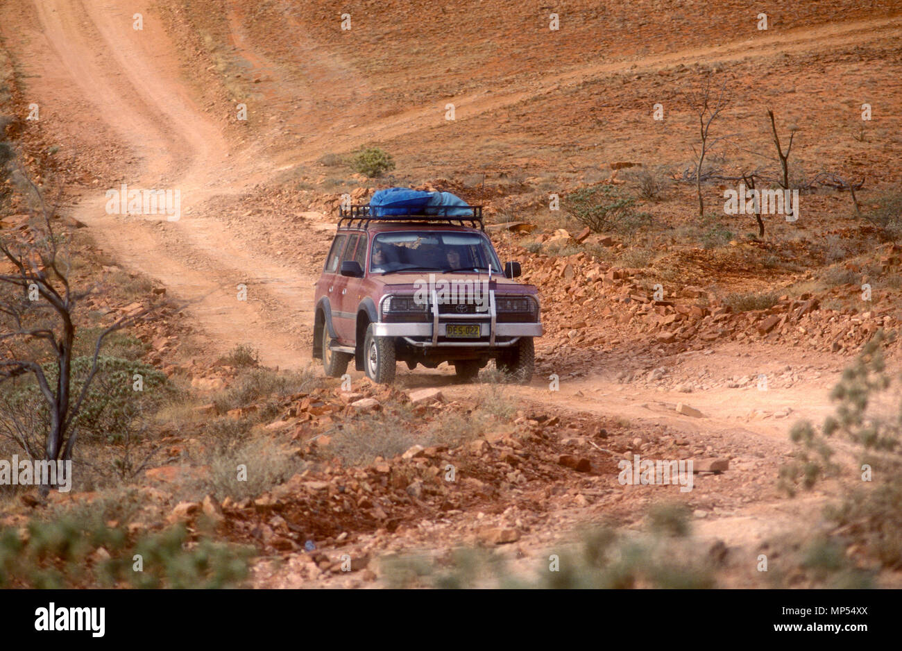 4WD VEHICLE TRAVELLING ALONG A DIRT ROAD NEAR CHAMBERS PILLAR, NORTHERN TERRITORY, AUSTRALIA Stock Photo