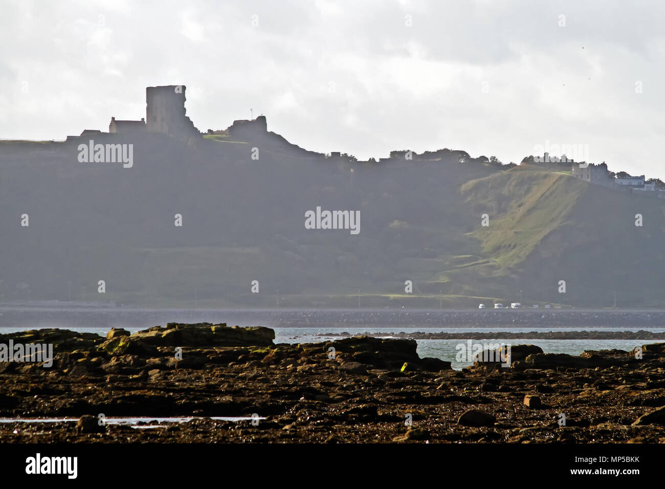 Scarborough’s Castle and headland towering above Marine Drive and North Bay, seen from across the bay at Crook Ness. Stock Photo