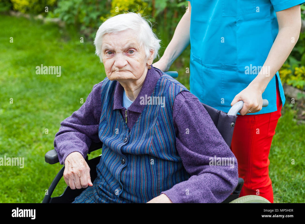 Senior disabled woman in wheelchair walking outdoor with female caretaker Stock Photo