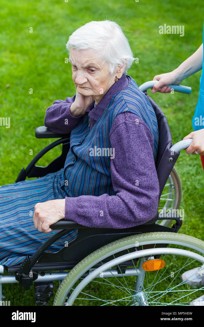 Senior disabled woman in wheelchair walking outdoor with female caretaker Stock Photo