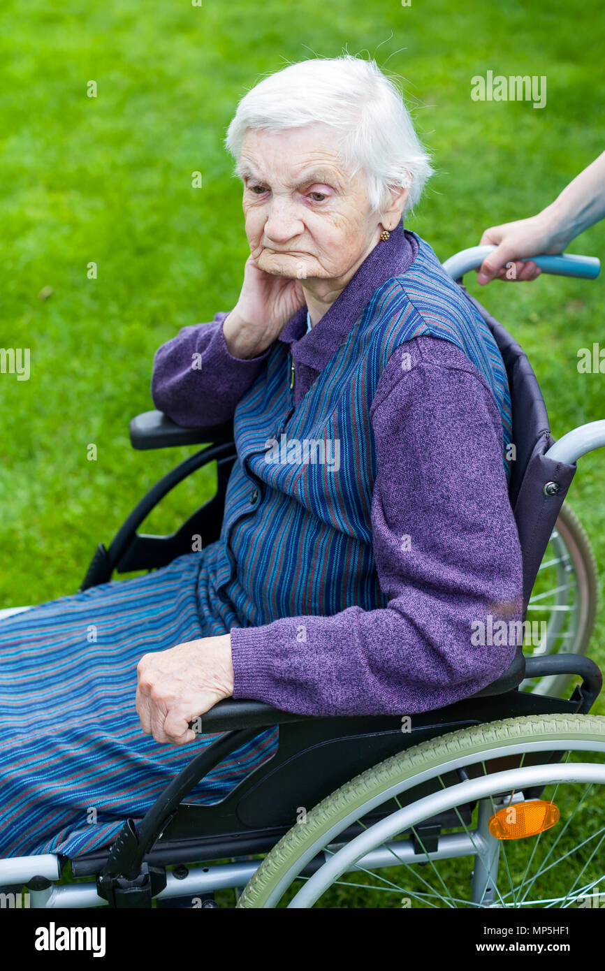 Senior disabled woman in wheelchair walking outdoor with female caretaker Stock Photo