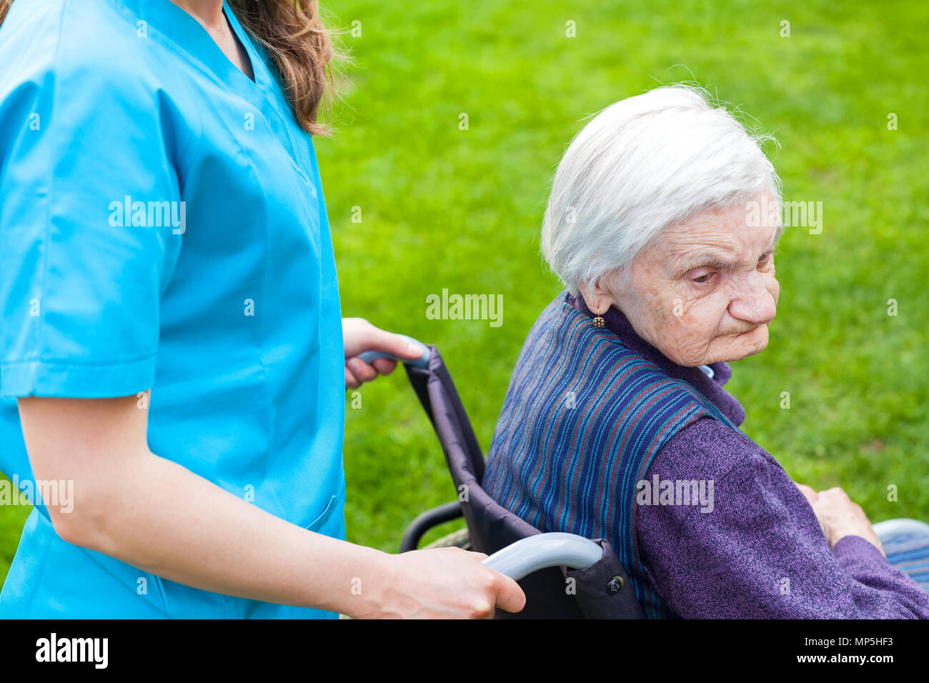 Senior disabled woman in wheelchair walking outdoor with female caretaker Stock Photo