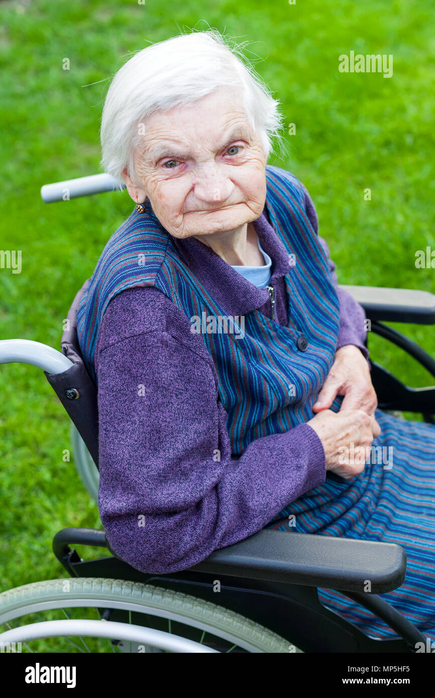Old lady sitting in wheelchair suffering from dementia spending time