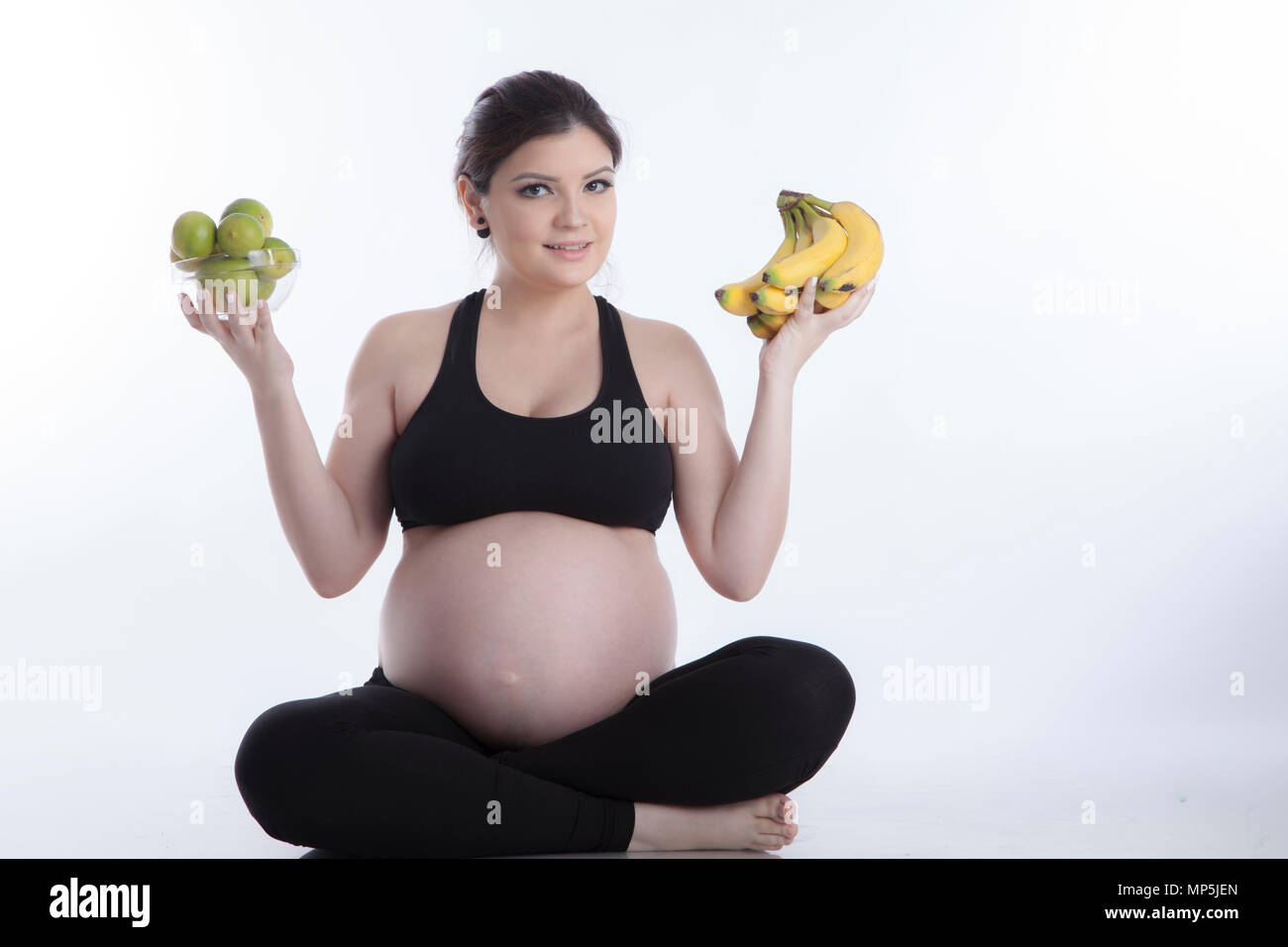 Healthy pregnant woman eating vitamin rich fruit over white background Stock Photo