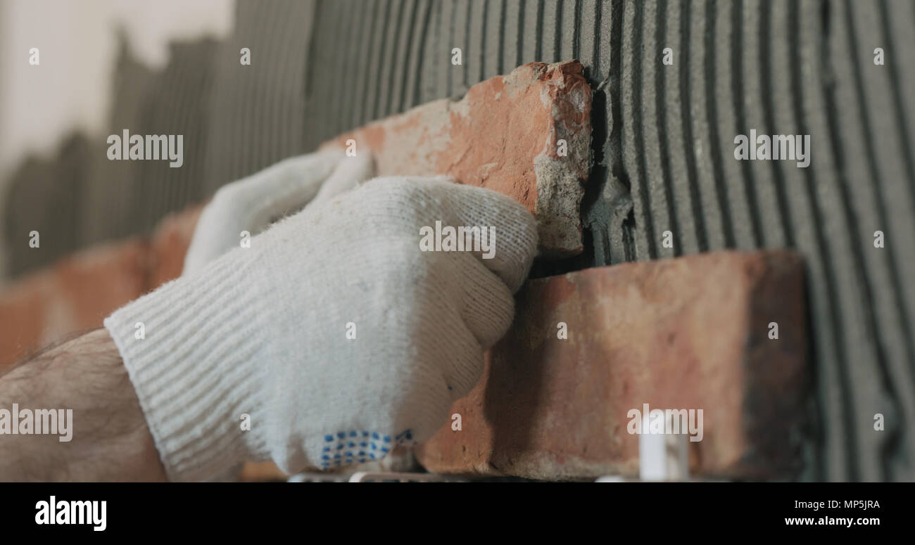 closeup worker applying brick cuts tile to the wall Stock Photo