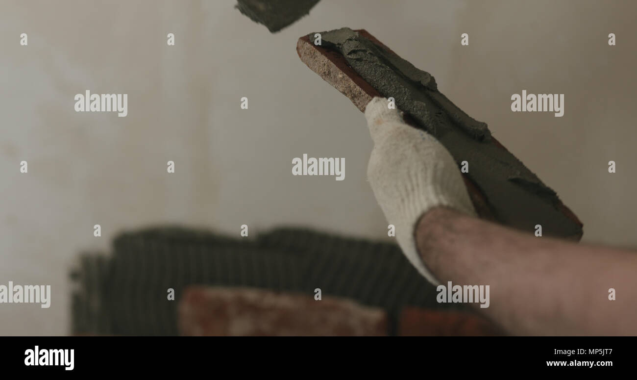 closeup worker applying concrete glue to brick cuts tile Stock Photo