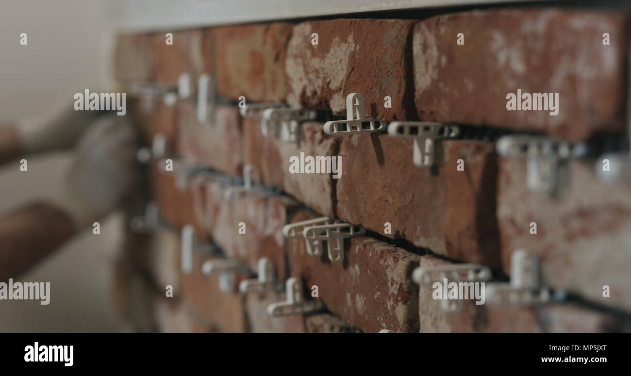 closeup worker applying brick cuts tile on the wall Stock Photo