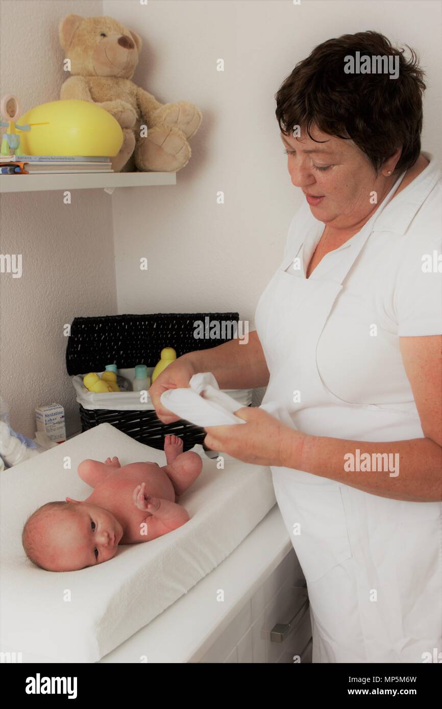 Dutch maternity nurse dressing up newborn baby,  as part of Dutch Kraamzorg. Stock Photo