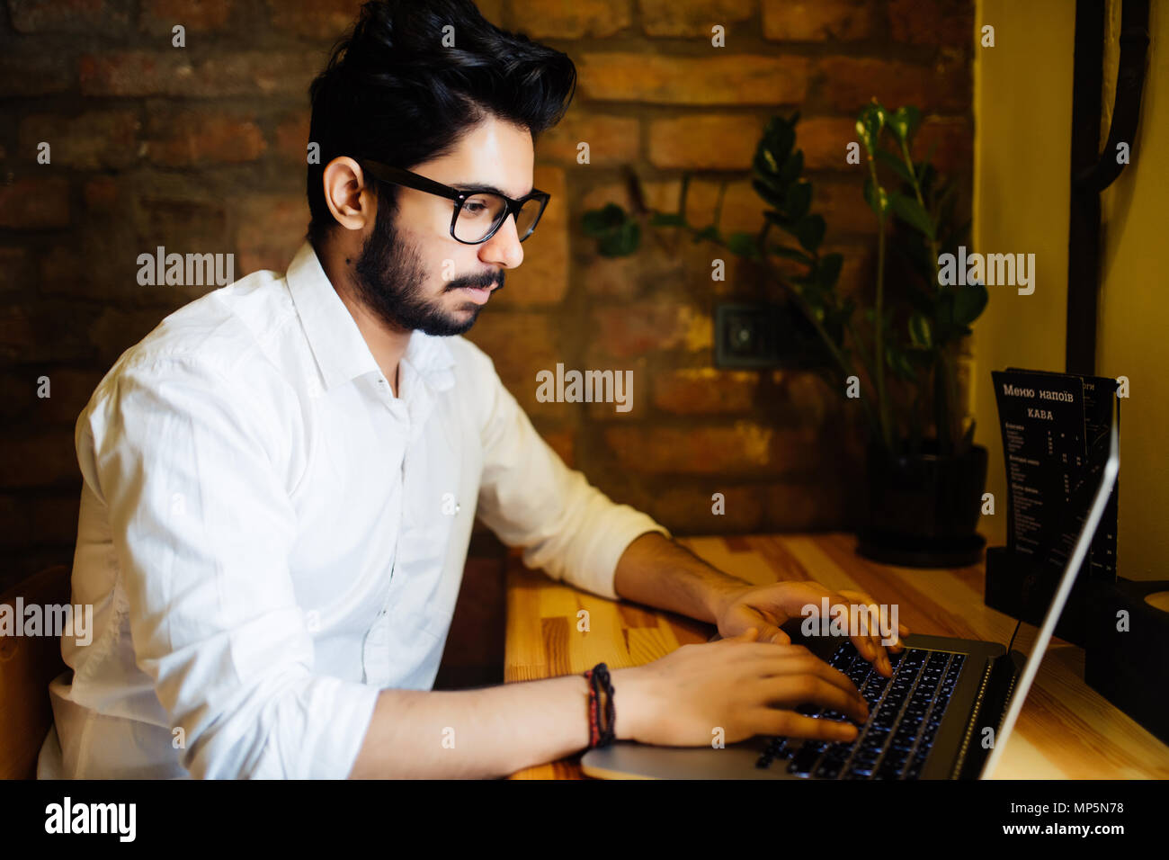 Attractive Asian indian Man in Cafe with laptop Stock Photo