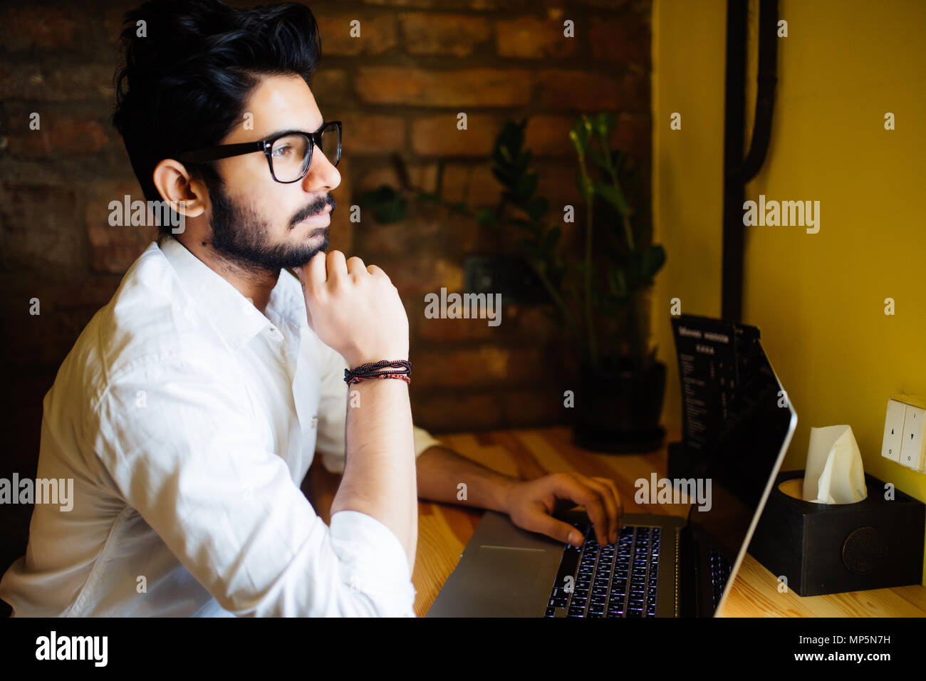 Attractive Asian indian Man in Cafe with laptop Stock Photo