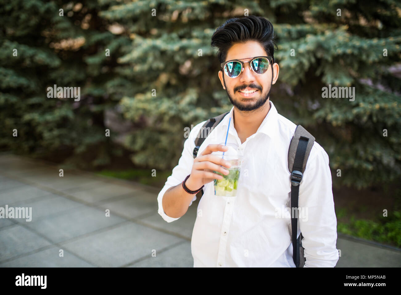 Portrait of young Indian man in sunglasses drink summer drink mojito in ...