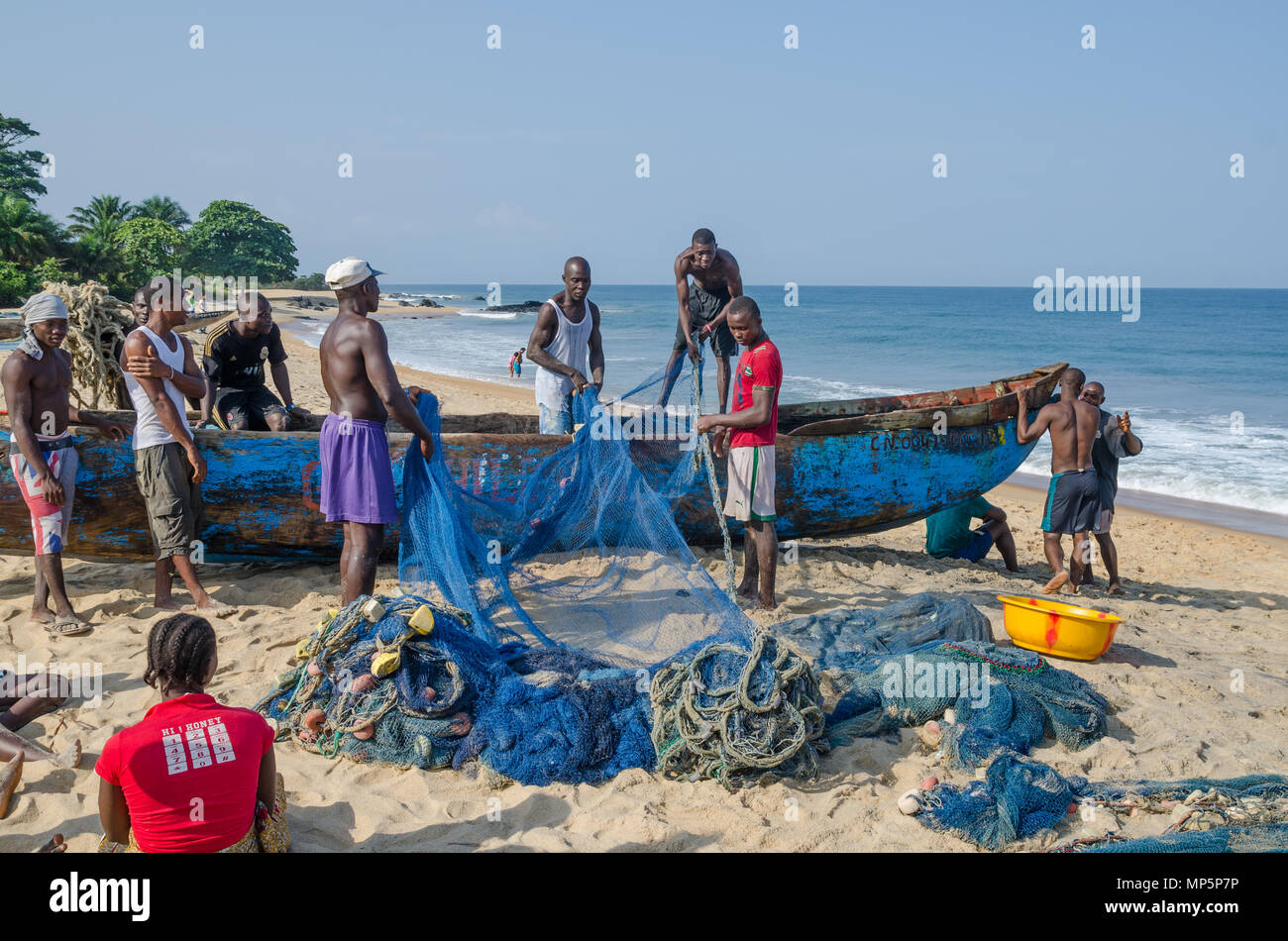 Fishermen sorting nets on wooden boat at beach Stock Photo