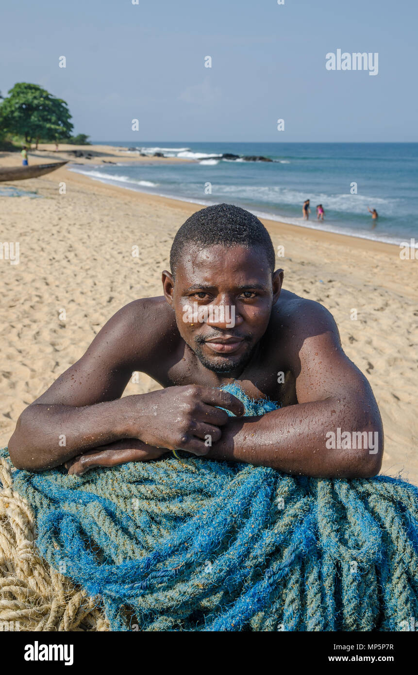 Portrait of African fisherman leaning on nets at beach Stock Photo