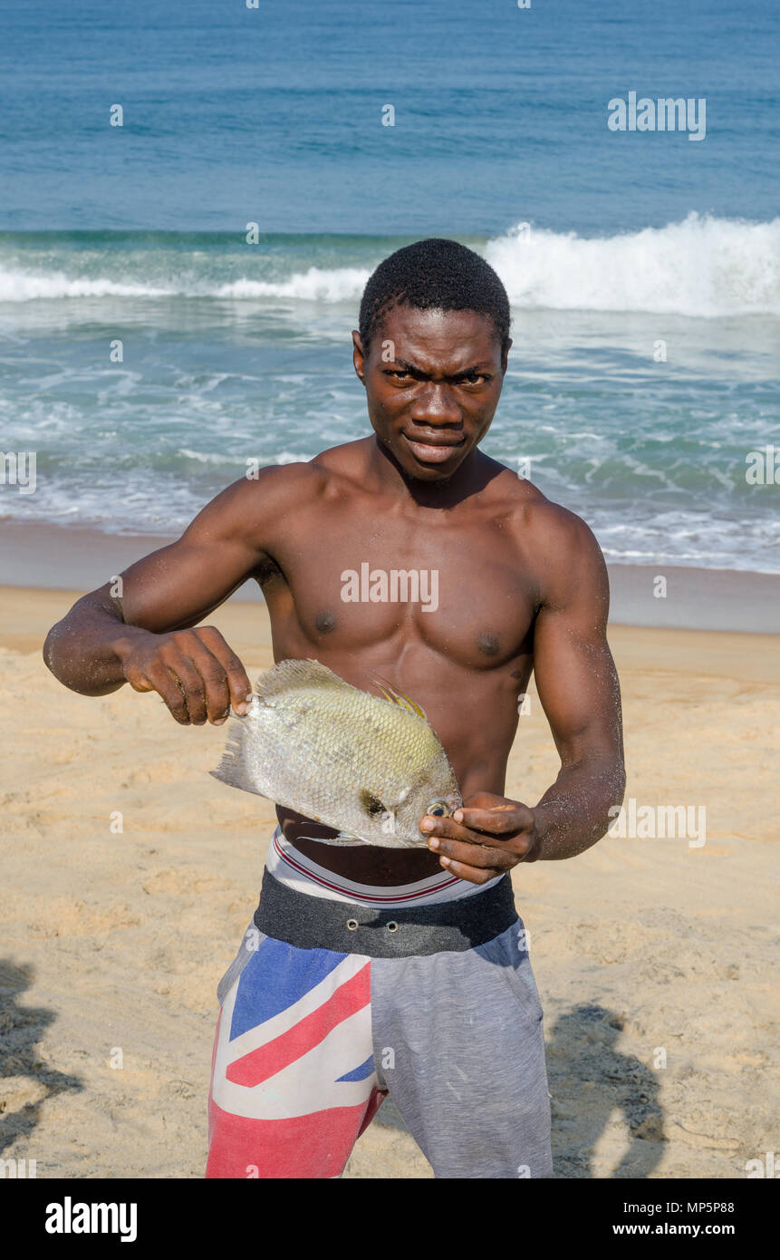 Portrait of African fisherman presenting catch at beach Stock