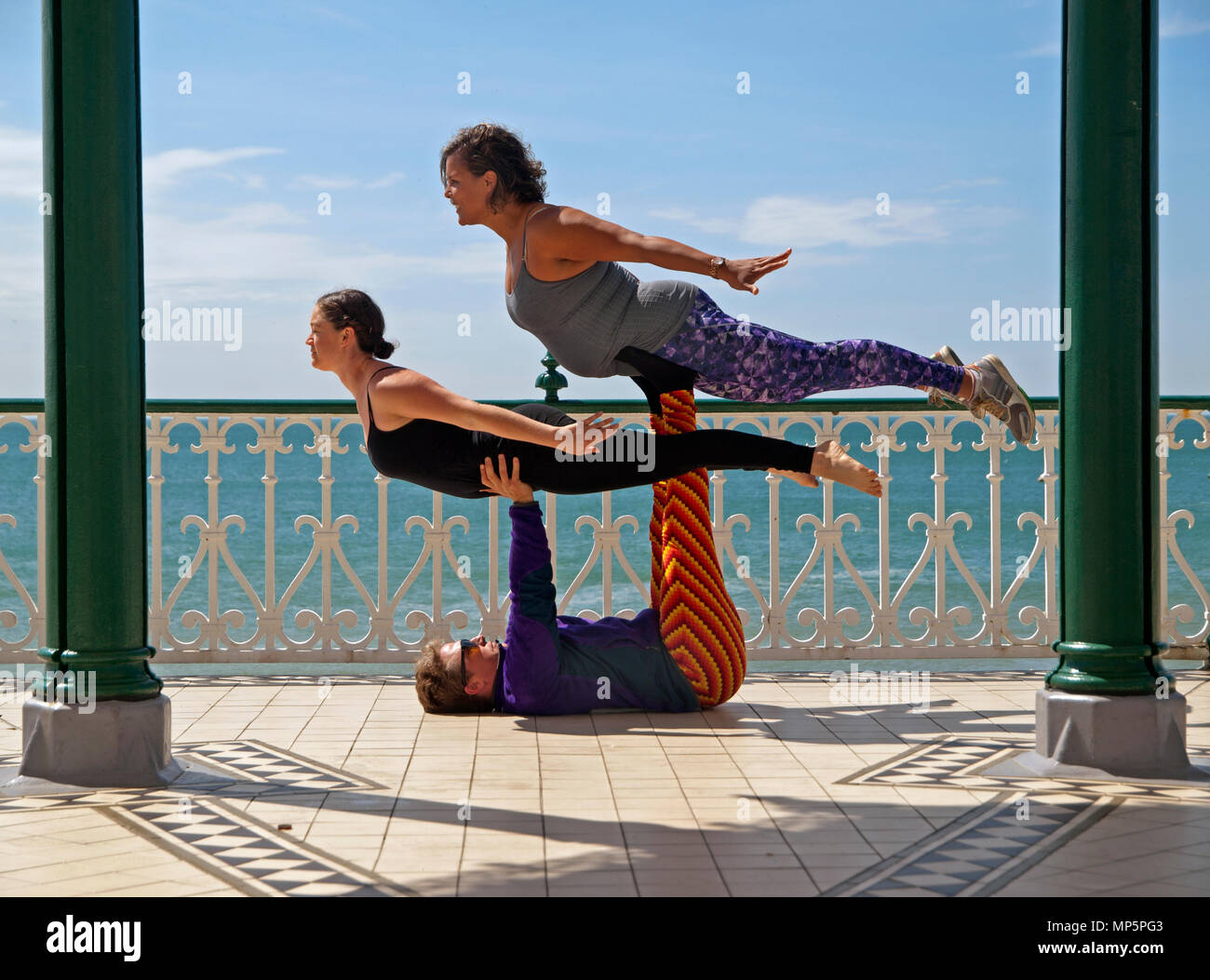 On the sunny Brighton seafront fit young people practice acroyoga Stock Photo