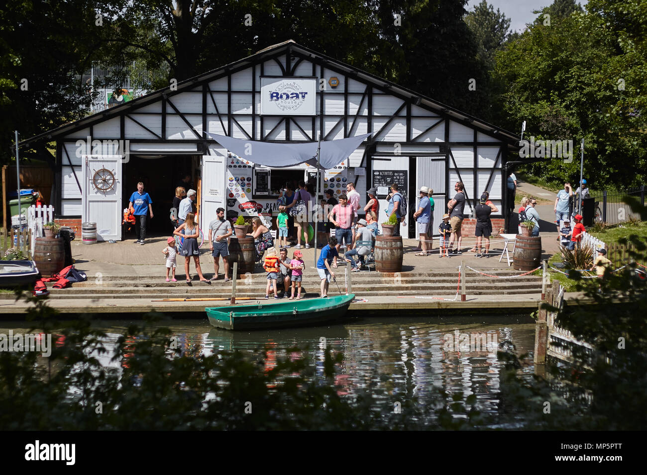 Families on a boat house quay on a sunny day. Pittville Park, Cheltenham, Gloucestershire. Stock Photo