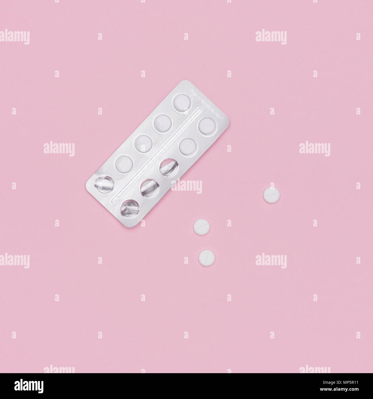 White pills and blister pack on pink pastel colored background. Pharmaceutical industry minimal still life flat lay background. Opioid epidemic. Stock Photo